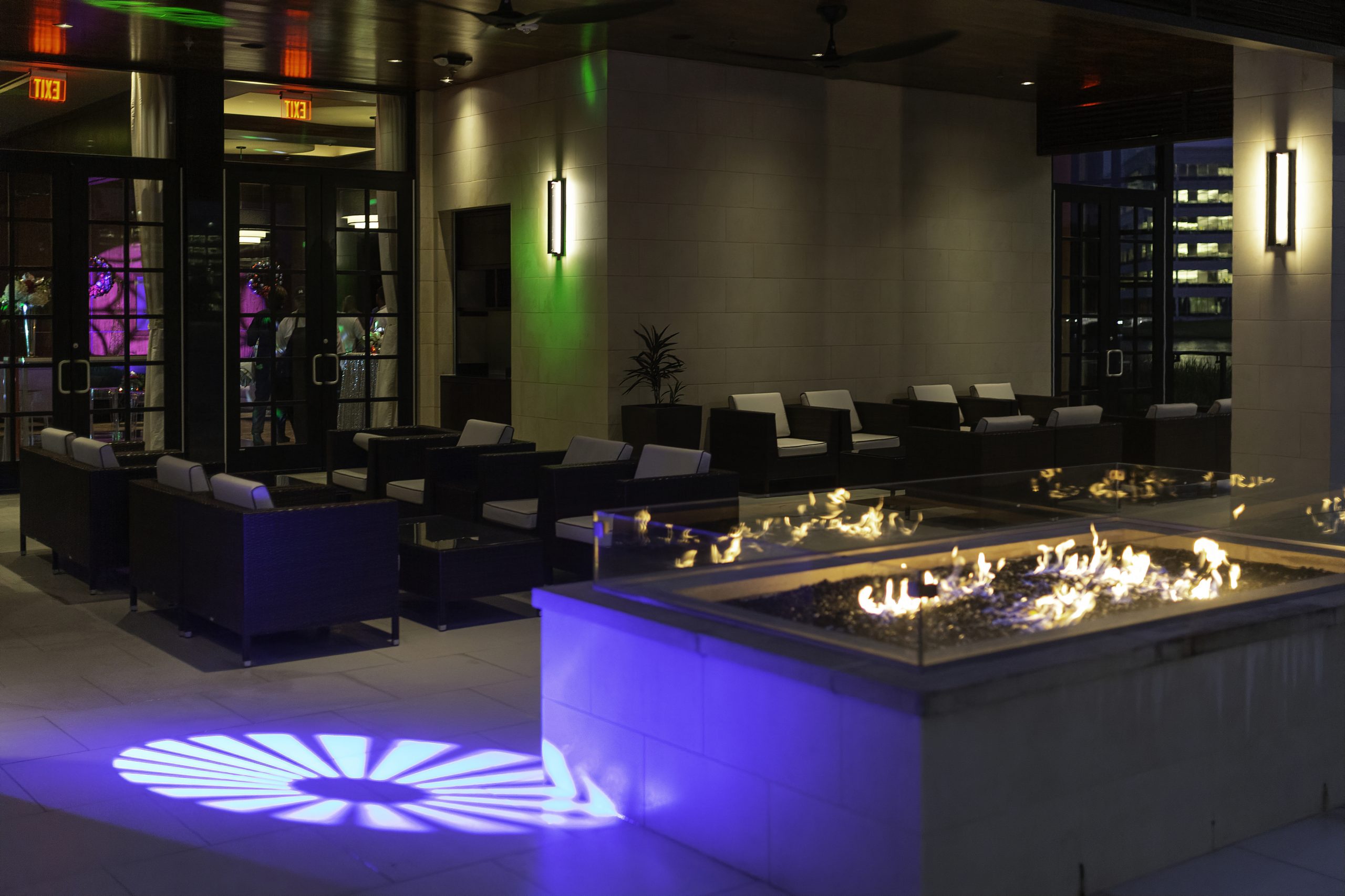 picture of Truluck's Woodlands private dining event on the outdoor terrace. Outdoor lounge style chairs and tables are surrounded by a luxurious gas fire pit and specialty lighting that was brought in to enhance the vibe.