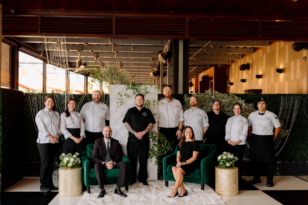 Truluck's Woodlands private dining team setup for a group photo on the outdoor terrace with a beautiful green and gold backdrop