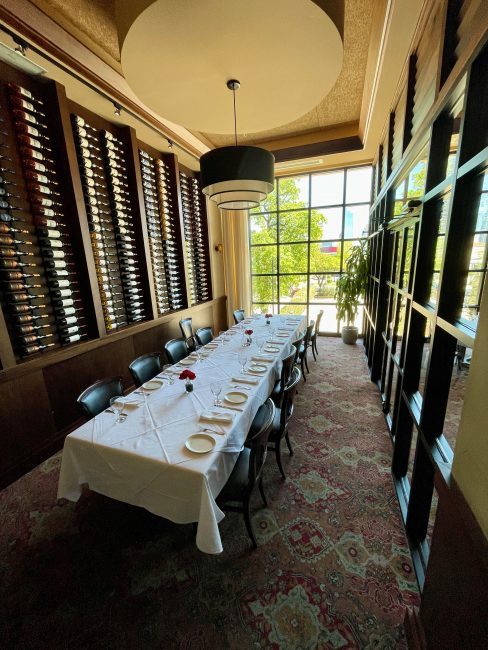 The Big Deal room in Dallas. This is a private room with wine bottles lining the far wall and floor to ceiling windows at the end of the room.