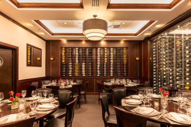 Elegant private dining room at Truluck’s Miami featuring floor-to-ceiling wine walls, beautifully set round tables, and warm wood accents for an upscale seafood dining experience.
