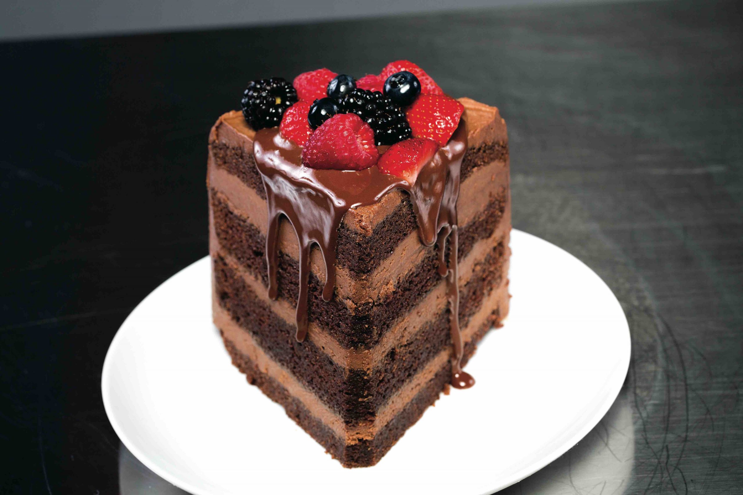 Chocolate malt cake with chocolate malt cream cheese icing drizzled with chocolate ganache and topped with strawberries, blueberries and blackberries