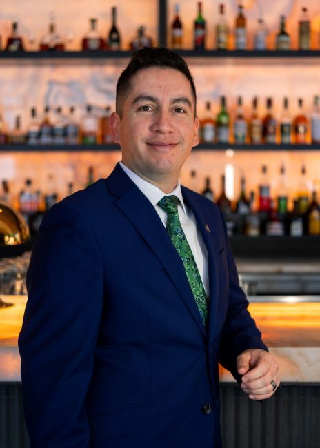 headshot of assistant general manager Fernando Nunez in a blue suit with his arm on the bartop