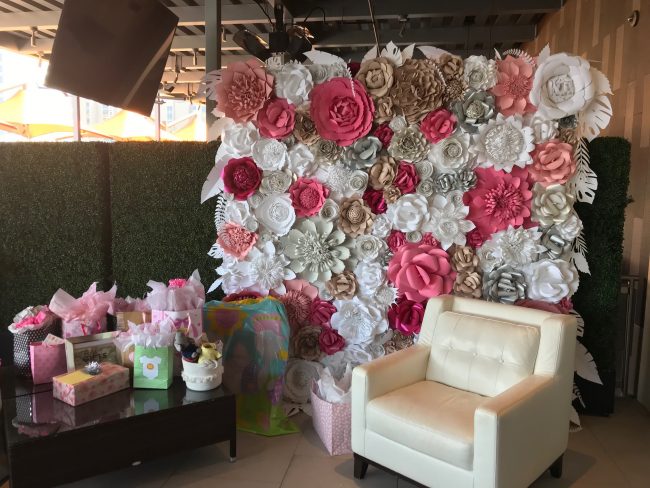 picture of Truluck's Woodlands baby shower with a floor to ceiling paper flower wall installed. The perfect back drop for mom-to-be to sit in the comfy white leather chair to open her gifts.