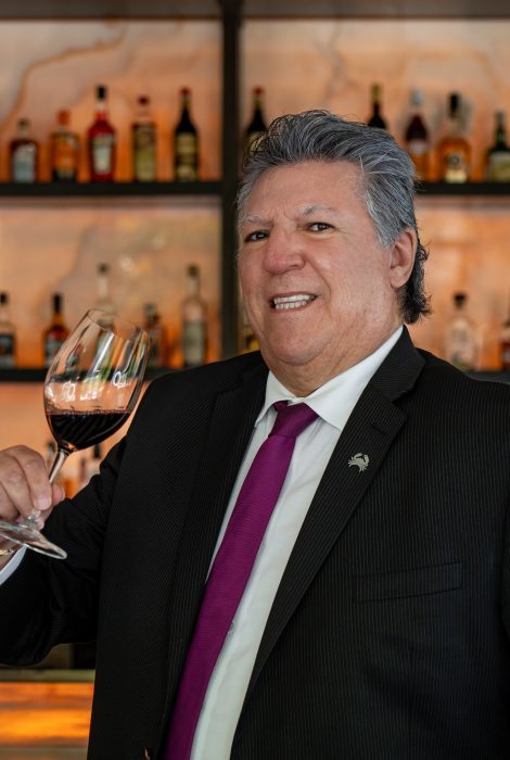 beverage manager Hector Garibay in front of the bar holding a glass of red wine