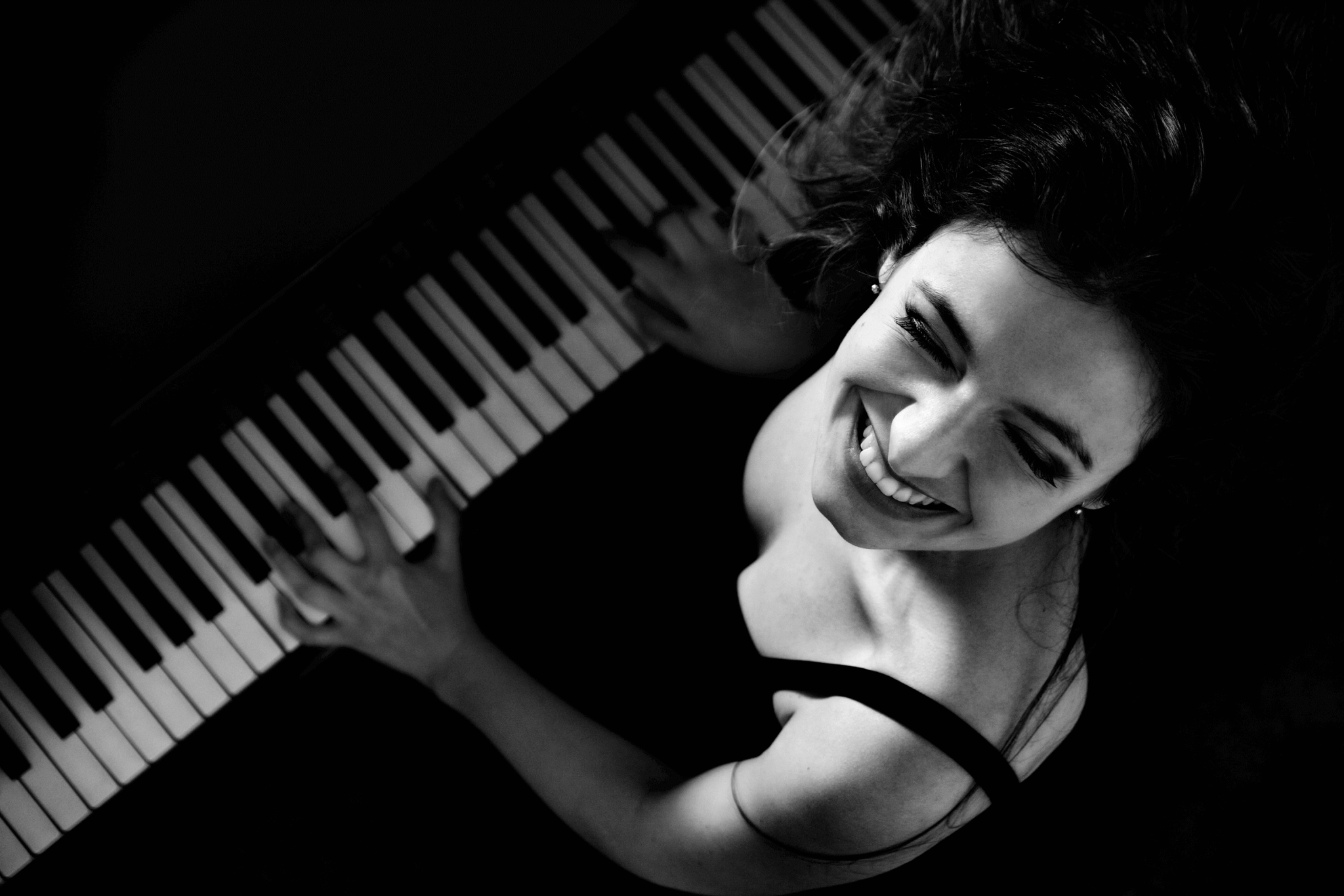 picture of Performer playing piano keys and smiling up at the camera