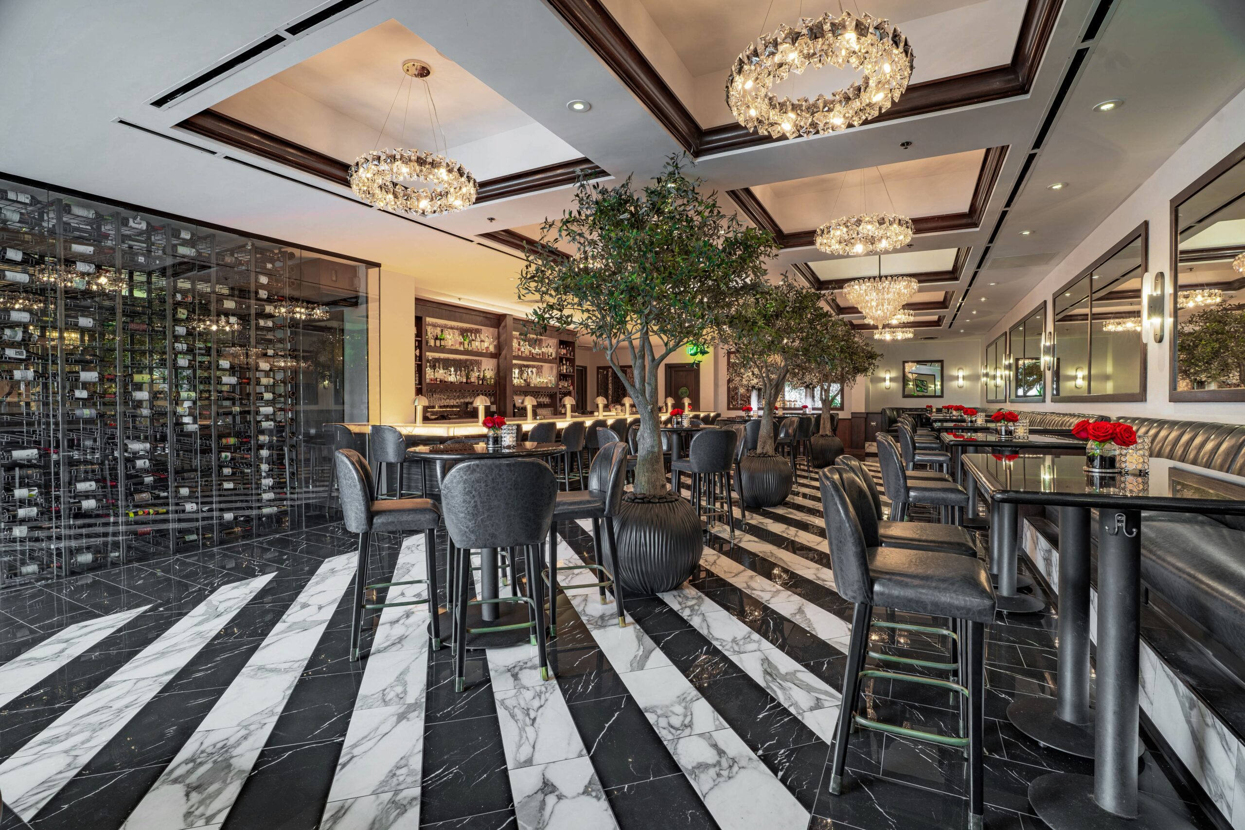 Truluck’s Houston lounge with marble floors, chandeliers, olive trees, and a luxury full bar.