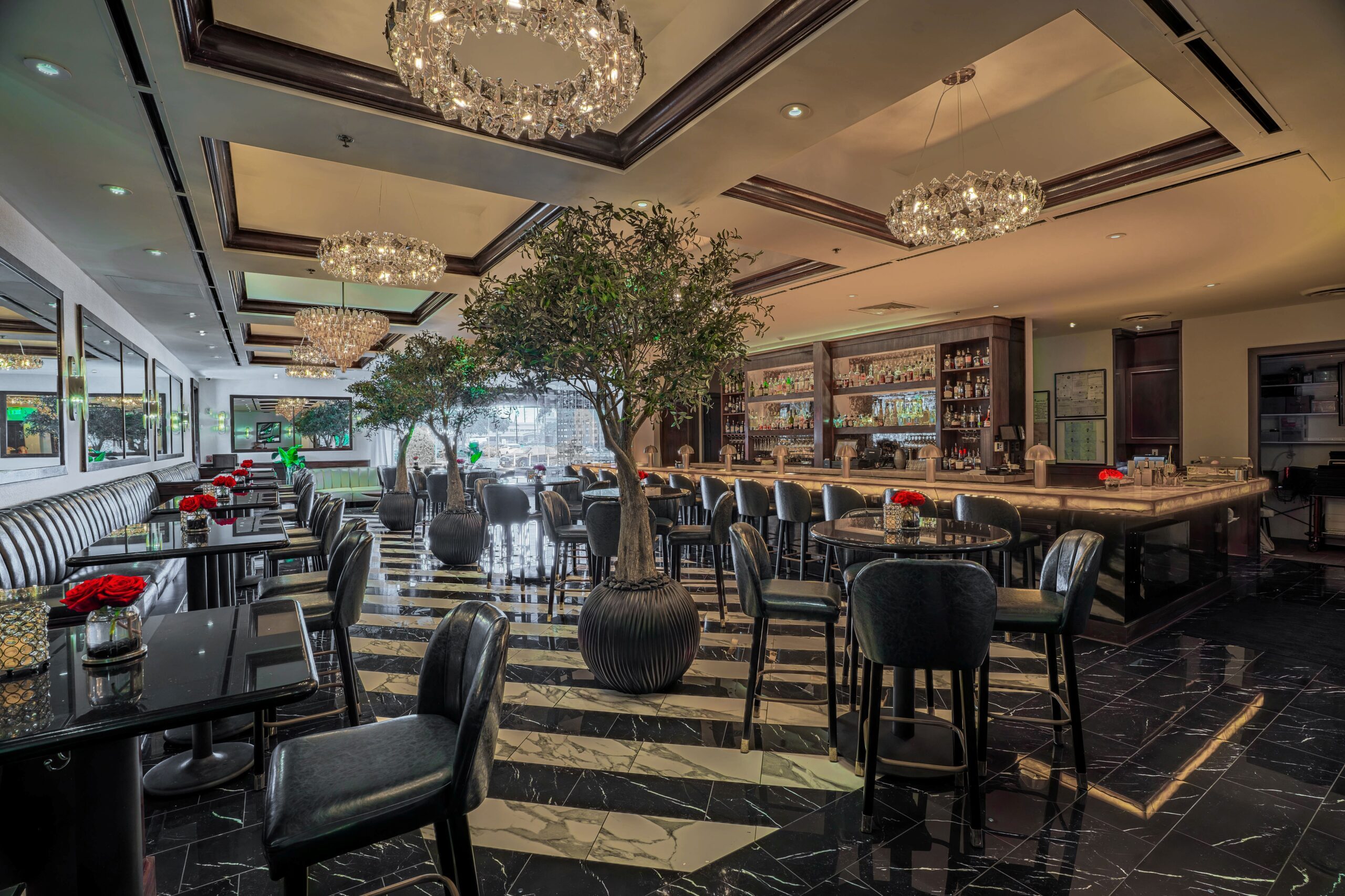 Truluck’s Houston lounge with marble floors, chandeliers, olive trees, and a luxury full bar.