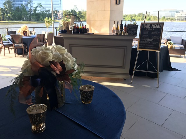 picture of Truluck's Woodlands private dining event. Specialty bar on the outdoor terrace with navy and copper accents and white rose centerpieces