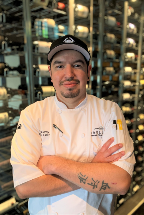 picture of Chef Michael Cerny in front of the wine wall at the restaurant