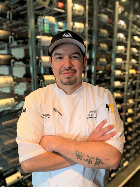 picture of Chef Michael Cerny in front of the wine wall at the restaurant