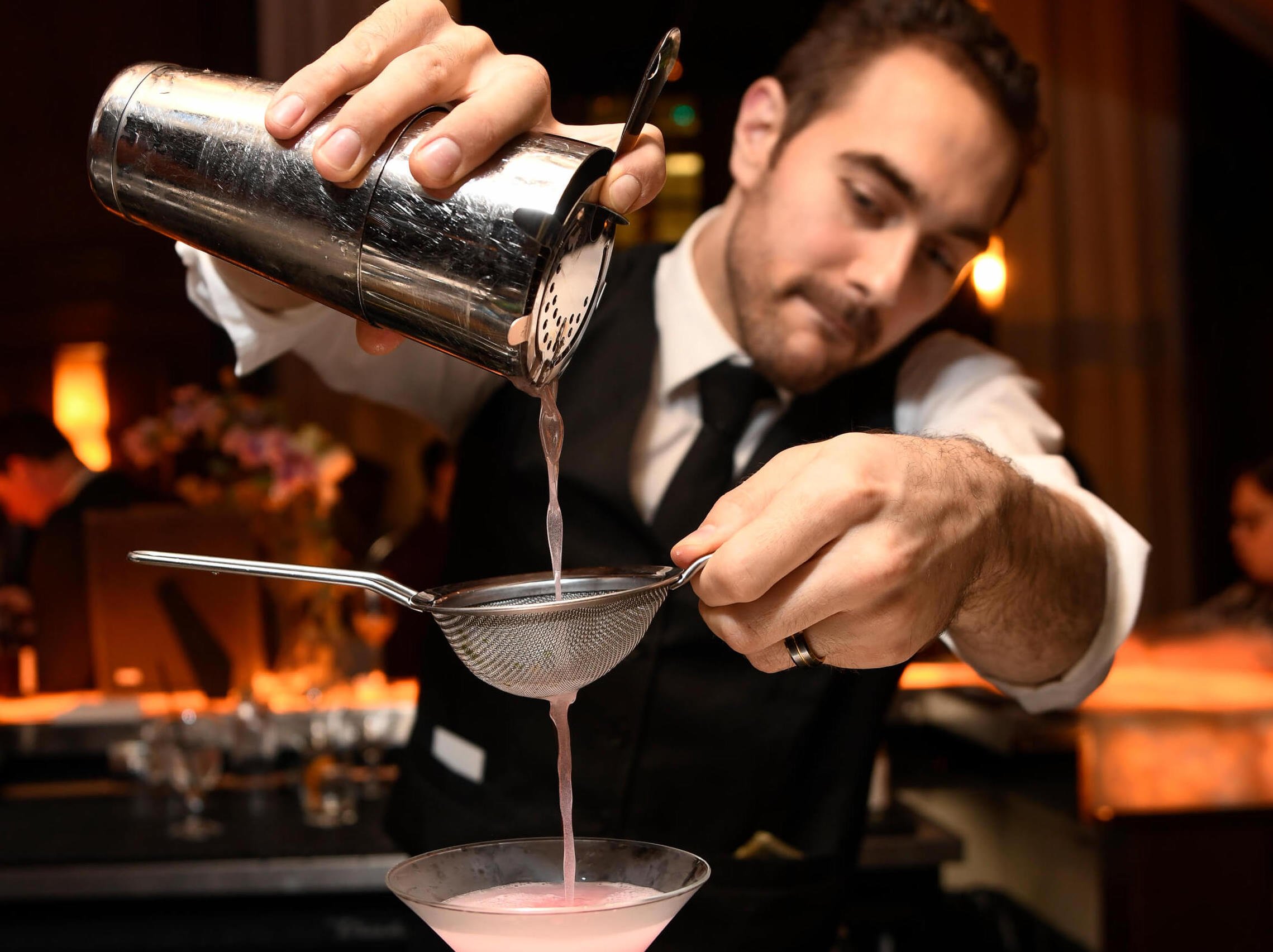 Truluck's bartender pours a cocktail through a filter from a shaker