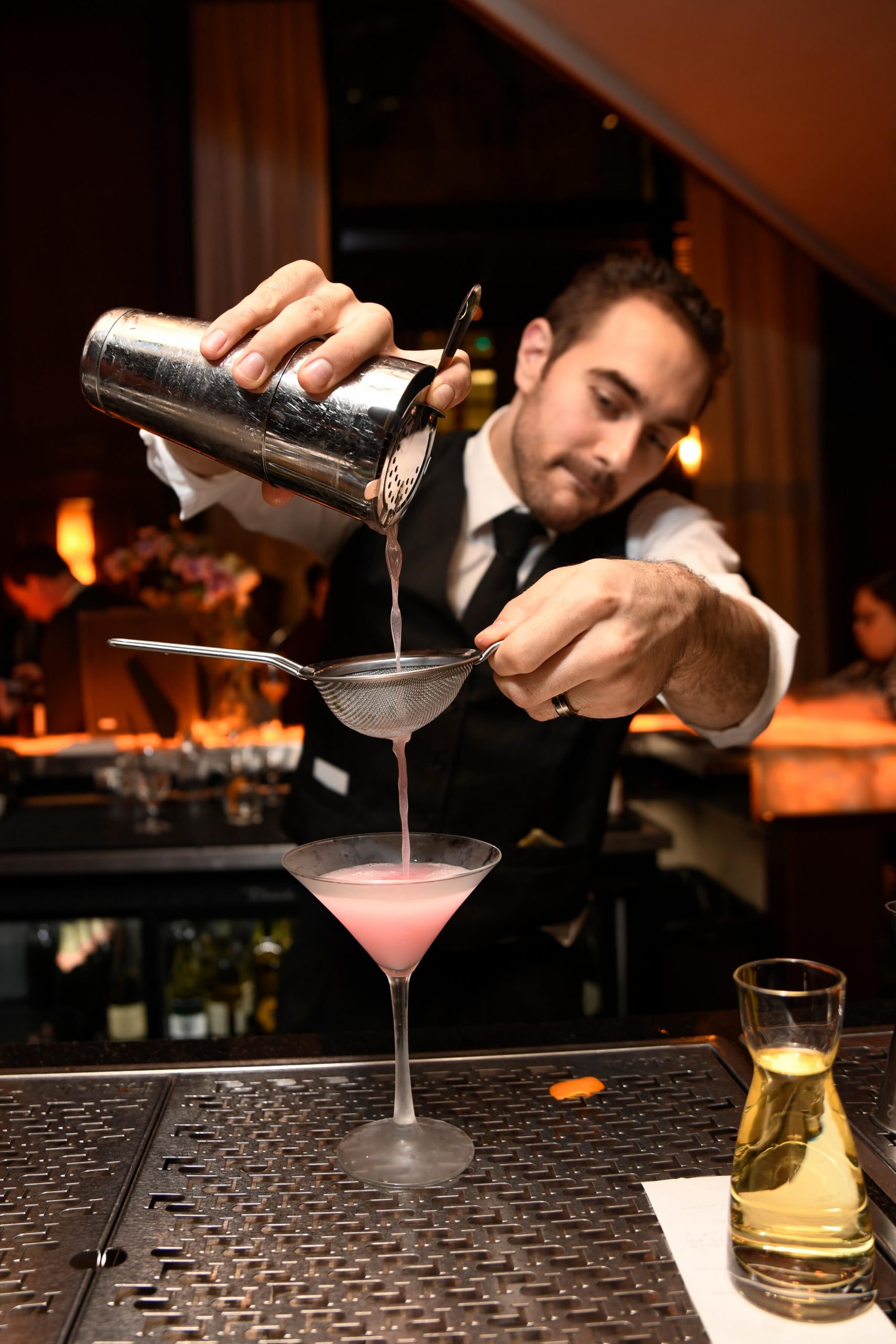 picture of Truluck's bartender pours a cocktail through a strainer from a shaker