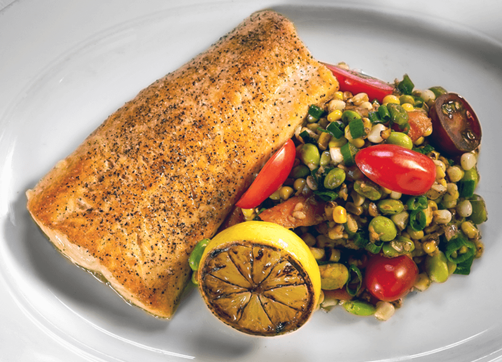 Fresh fish served with a fresh lemon ready to squeeze and paired with a fresh corn salad with tomatoes, lima beans, and green onion