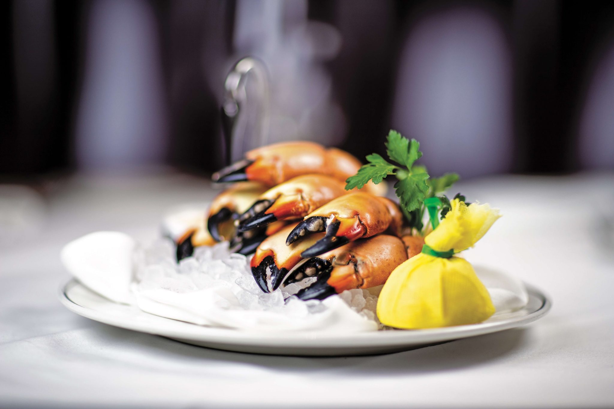 Florida stone crab legs, laying on ice with a fresh lemon ready to squeeze