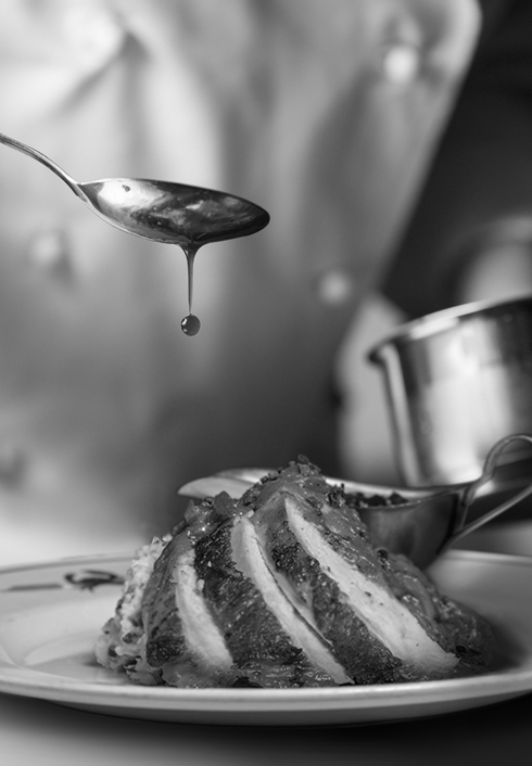 Sauce being drizzled over a plate of sliced turkey