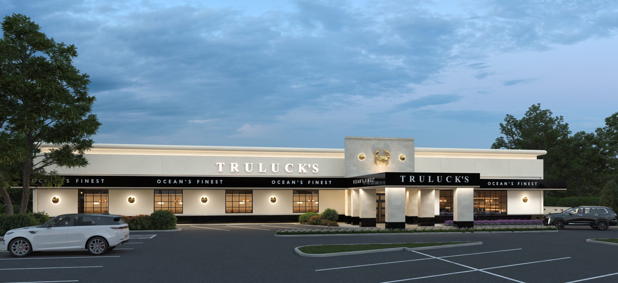 The exterior of Truluck's Houston with a white colored stone building featuring black awnings, TRULUCK'S in gold letters across the top and a large illuminated gold crab on the building