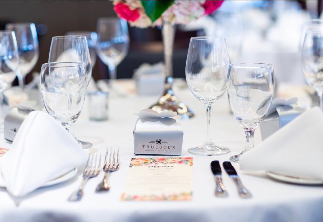 picture of Truluck's private dining table dressed in all white with a take away box of chocolates in a silver Truluck's box.