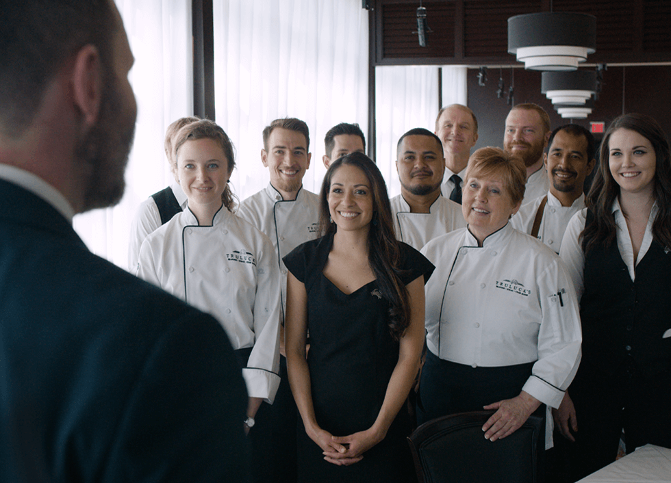 Team of Truluck's staff and chefs smile while listening to head manager