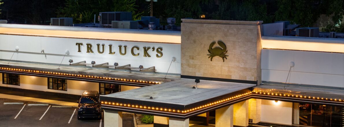 image of exterior of Truluck's Houston at twilight with glowing exterior lights and TRULUCKS in gold letters with a crab icon on the building