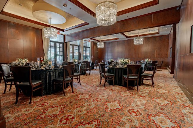 The Stone Crab Room at The Woodlands location. Black sequin table cloth draped tables with mahogany wood chairs, crystal chandeliers and windowed French doors leading to the outdoor terrace.