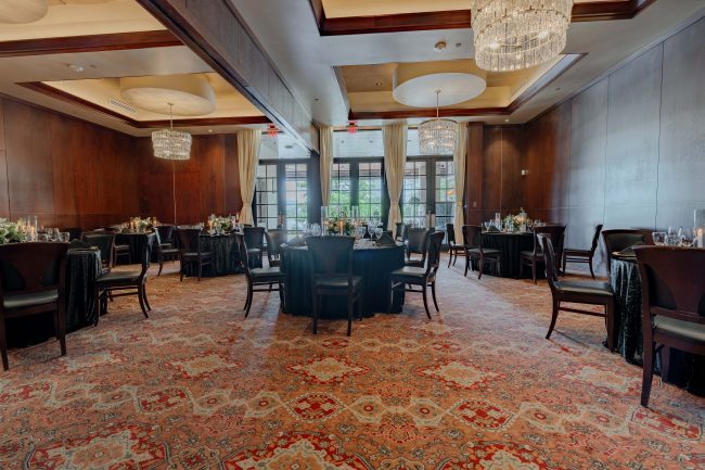 The Stone Crab Room at The Woodlands location with round tables draped in black sequin table clothes surrounded by mahogany wood chairs.