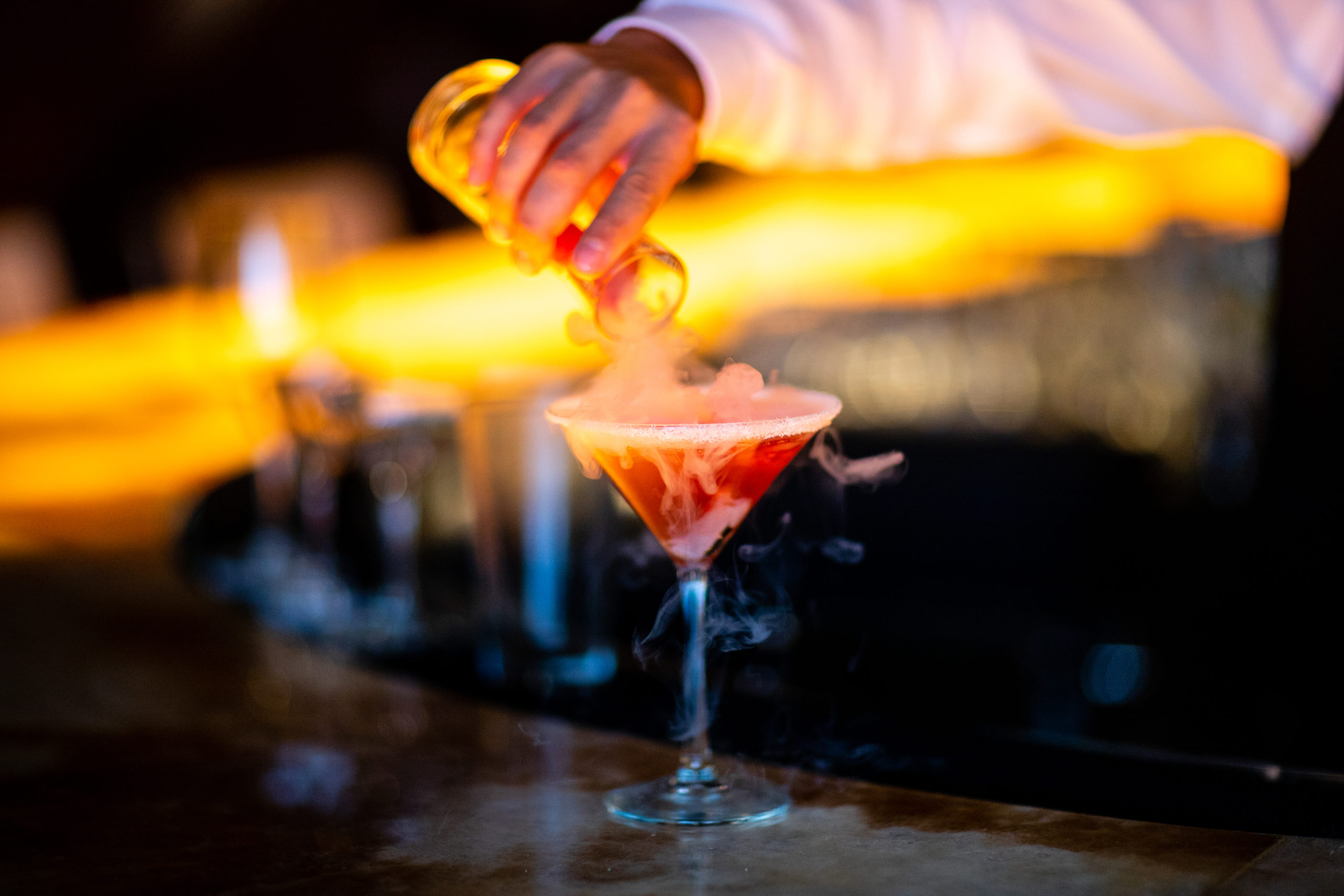 The bartender pouring a Voila! cocktail on the bartop