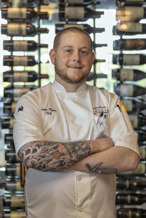 picture of chef partner Shane Flynn in front of the wine wall at the restaurant