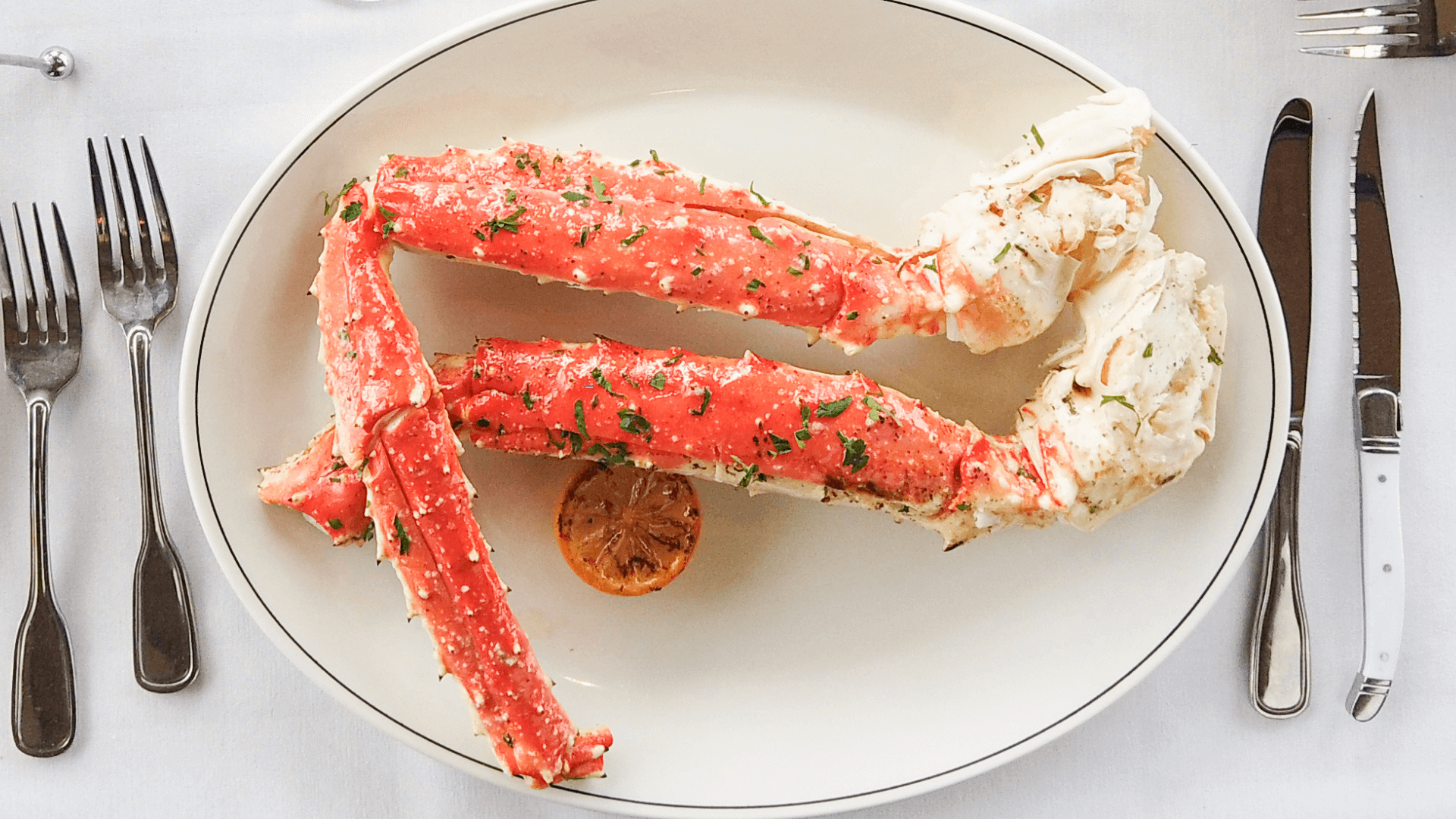 picture of Alaskan king crab legs on a plate with a lemon wheel and silverware