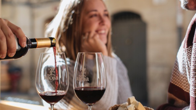 picture of Rioja wine being poured with a lady smiling in the background