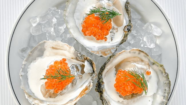 picture of Belon oysters topped with creme fraiche, Ora King caviar and fresh dill on a bed of ice