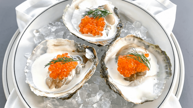 picture of Belon oysters on the half shell topped with creme fraiche, Ora King caviar and fresh dill on a bed of ice