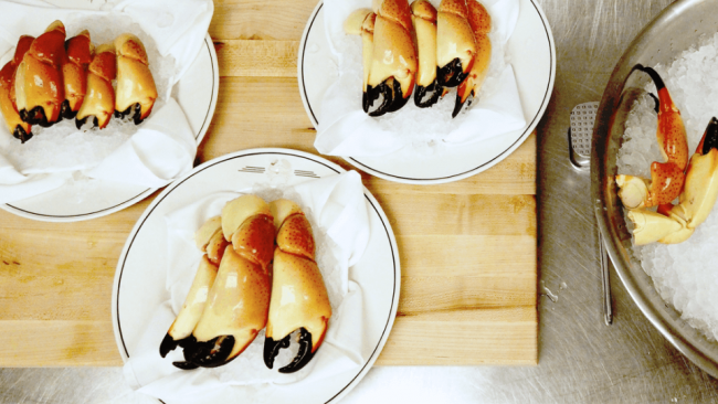 picture of 2 plates of stone crab claws atop a cutting board in the kitchen