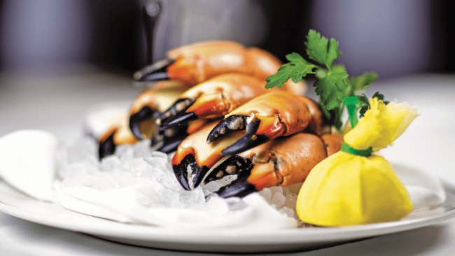 picture of fresh Florida stone crab claws on ice with a wrapped lemon and sprig of parsley