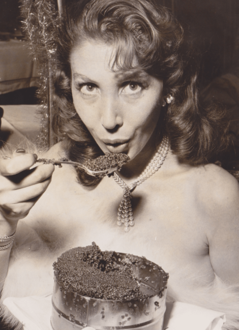 picture of a lady with a spoonful of caviar and a tin of caviar about to take a bite