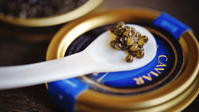 picture of Black River caviar on a pearl spoon with the spoon sitting on the caviar tin lid