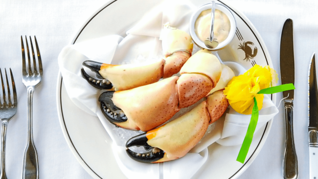 picture of 3 jumbo Yucatan crab claws on a plate with a lemon wrap and mustard sauce