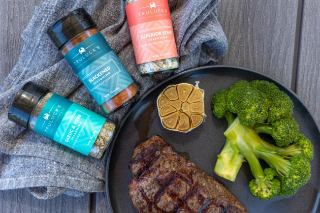 picture of Truluck's seasonings next to a plate of steak and broccoli