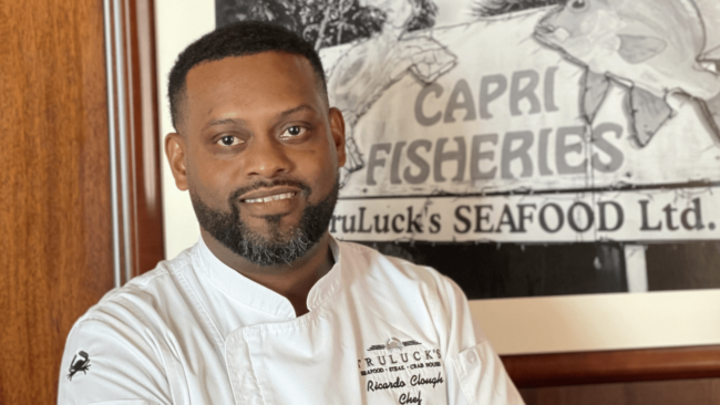 Chef Ricardo in front of a sign that says "Capri Fisheries, Truluck's Seafood, LTD"