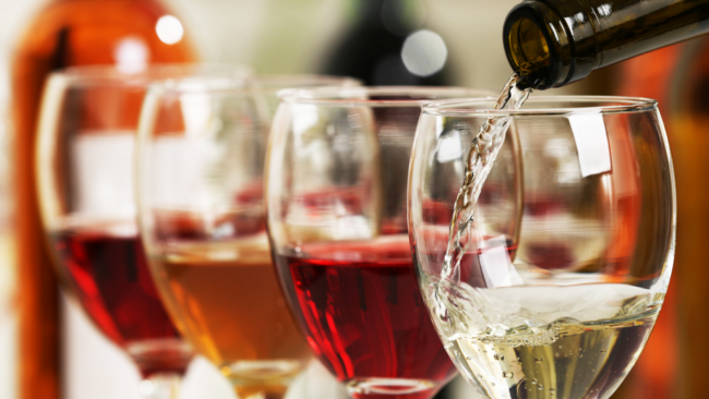 picture of several glasses of wine in a row with the front glass having wine poured into it