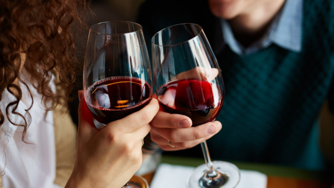 picture of a couple toasting red wine glasses