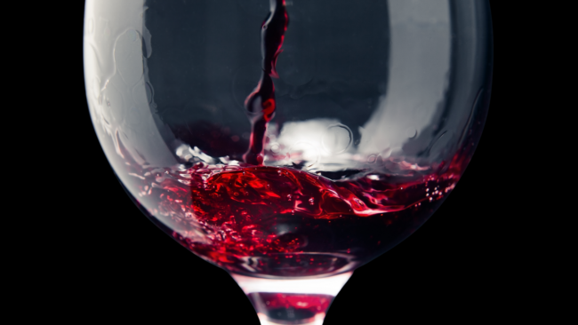 close up picture of red wine being poured into a wine glass