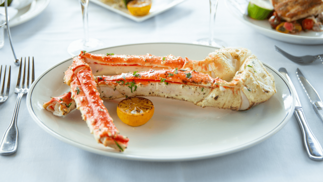 photo of 2 large red king crab legs on a plate with a grilled lemon