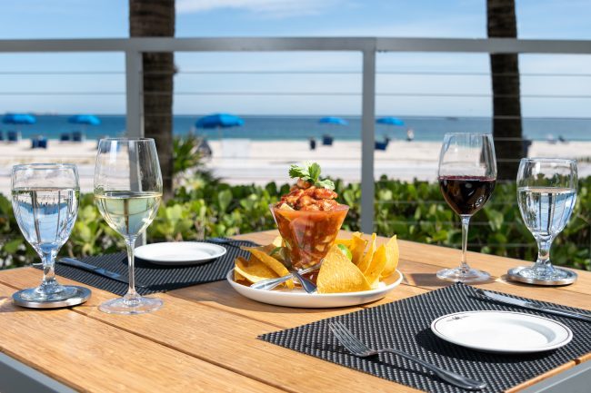 view of the ocean and beach from the Truluck's Fort Lauderdale patio with a glass of campechana seafood and chips on the table