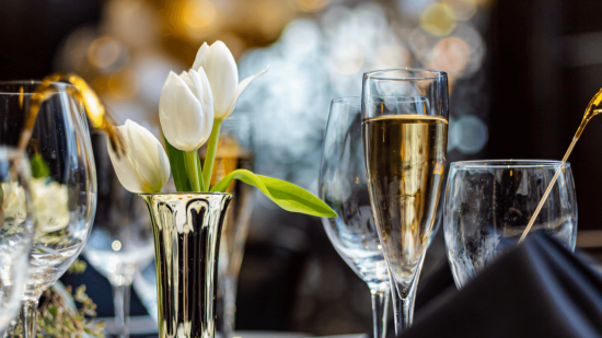 photo of white tulips in a vase on a table with champagne and water glasses