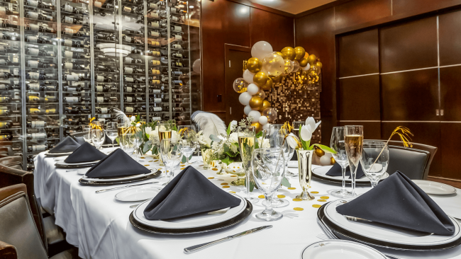 photo of a private dining room able with black and gold decorations including a balloon wall backdrop