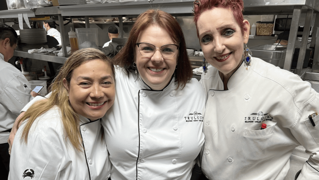 Truluck's server team hugging and smiling while in the kitchen area