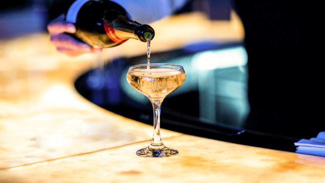 photo of a glass of champagne being poured on the amber bar top