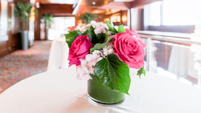 photo of a vase with pink roses and pink hydrangea with greenery on a white clothed table
