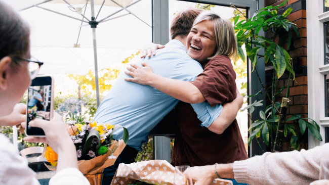 photo of a mom and her son hugging while another family member takes a picture