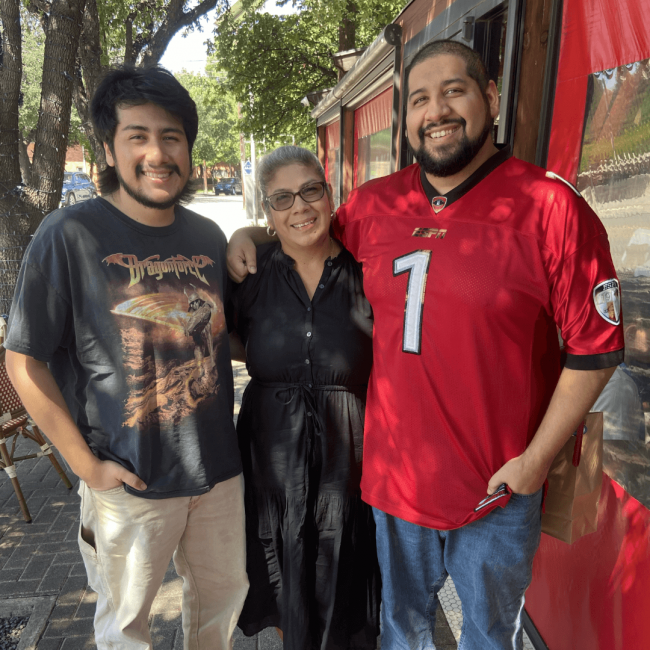 Mary with her two sons by a food truck all smiling with their arms around each other